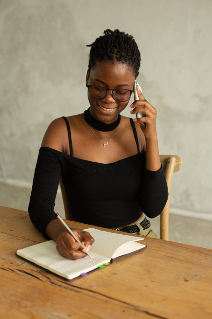 woman writing on a paper talking on the phone